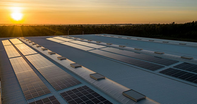 Wide shot of solar panels on a roof at sunset