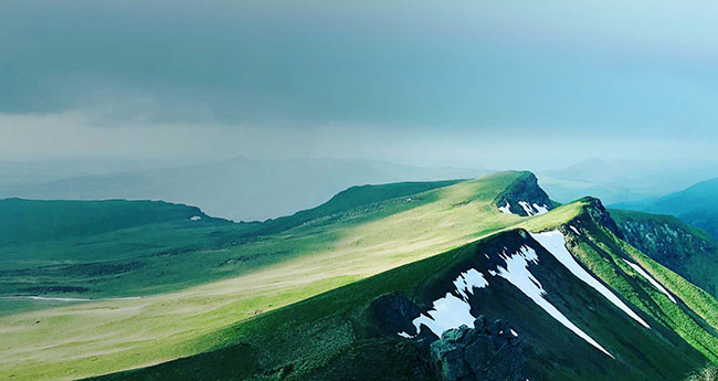 Aerial view of a mountain with grass and snow